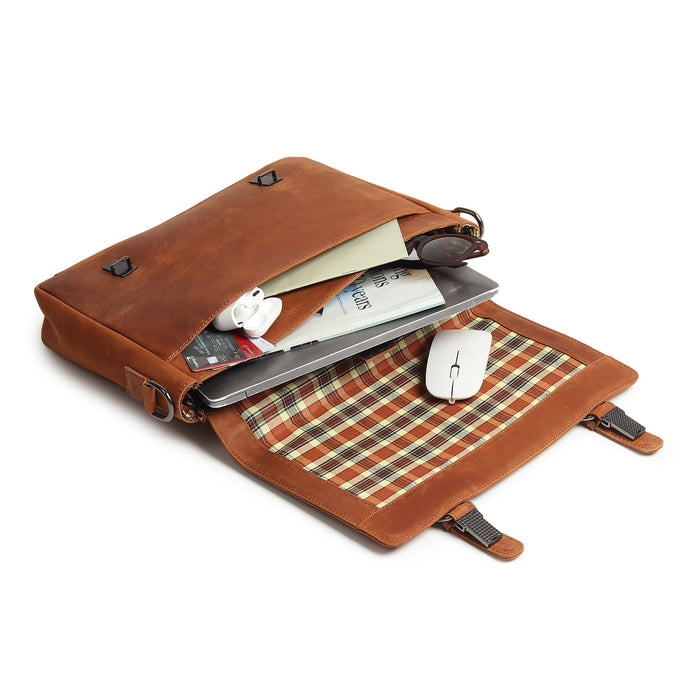 Brown leather bag with plaid lining containing a laptop, mouse, and other items on a white background